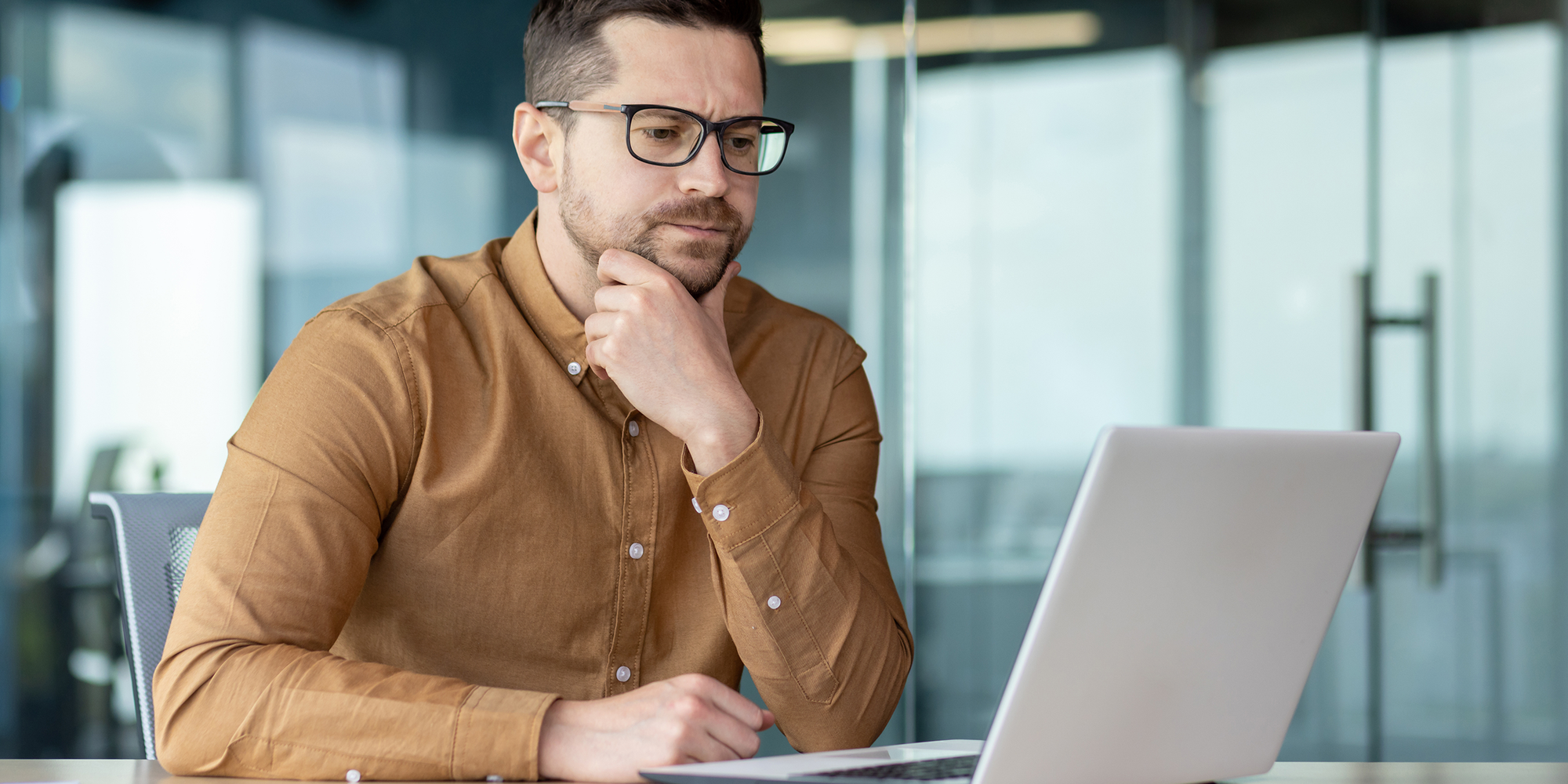 Büroarbeiter schaut prüfend auf Laptop